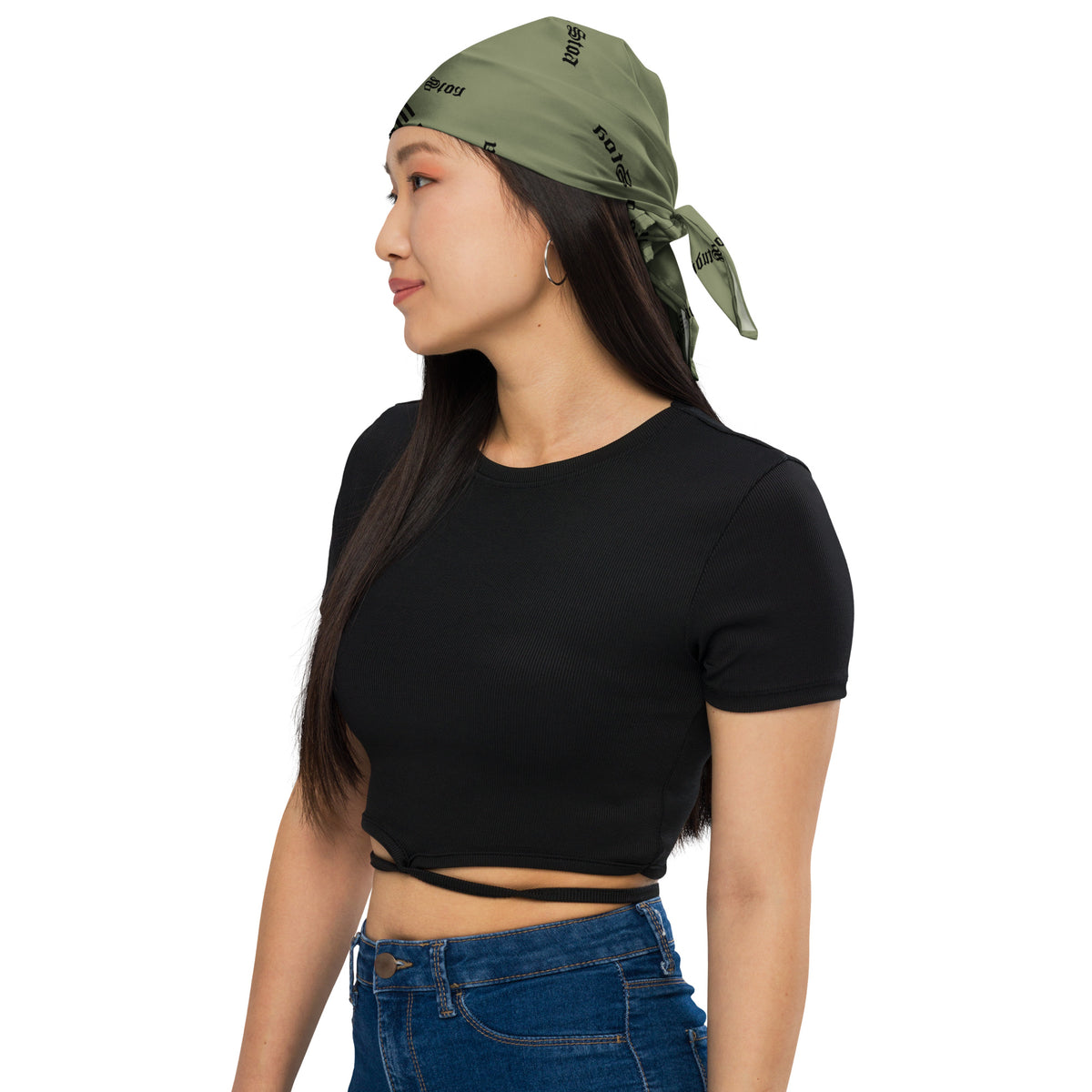 A woman wearing an olive green square bandana featuring a horizontal black-and-white American flag stripe pattern across the center, with a repeating black 'studio stoa' logo printed all over the fabric.