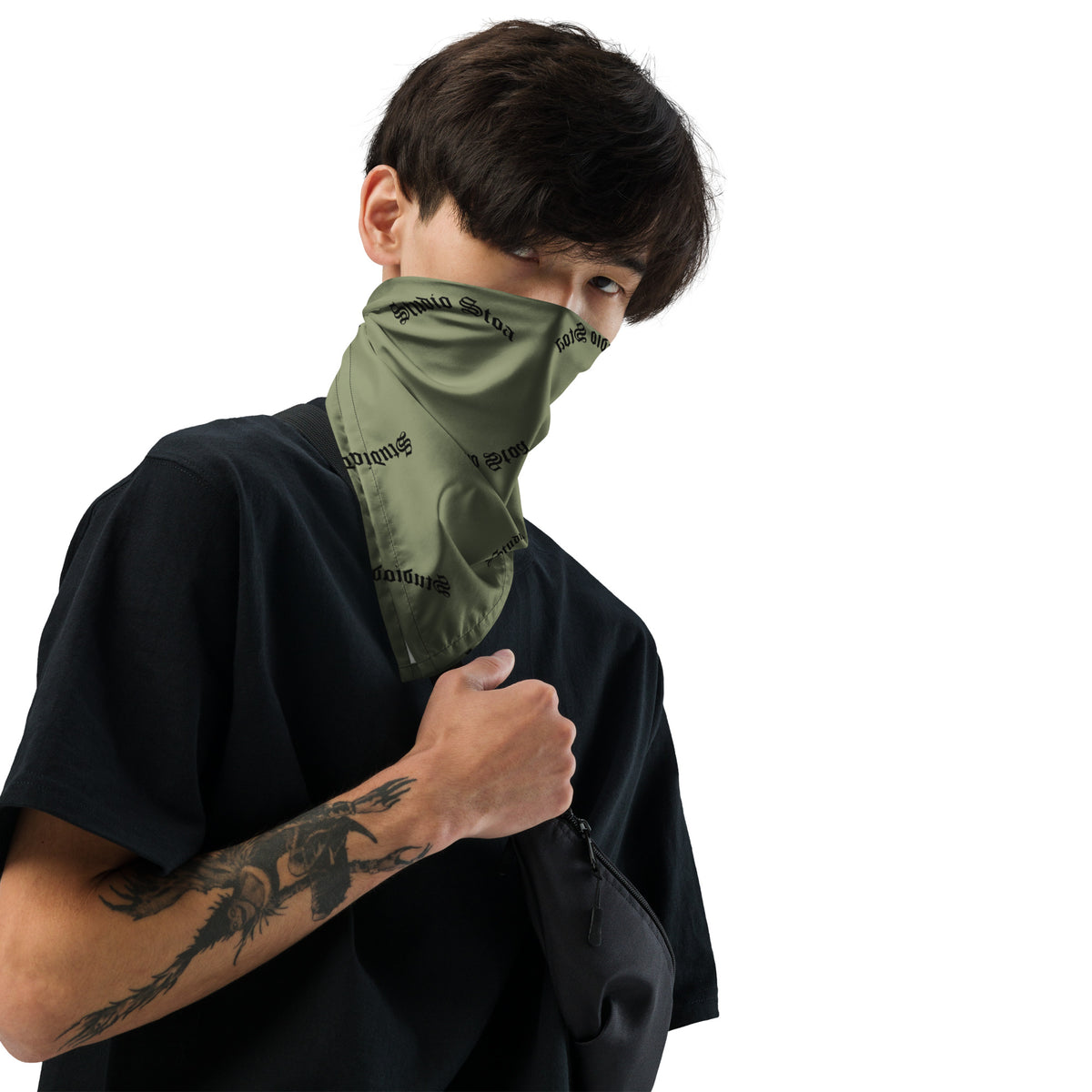 A man wearing an olive green square bandana featuring a horizontal black-and-white American flag stripe pattern across the center, with a repeating black 'studio stoa' logo printed all over the fabric.