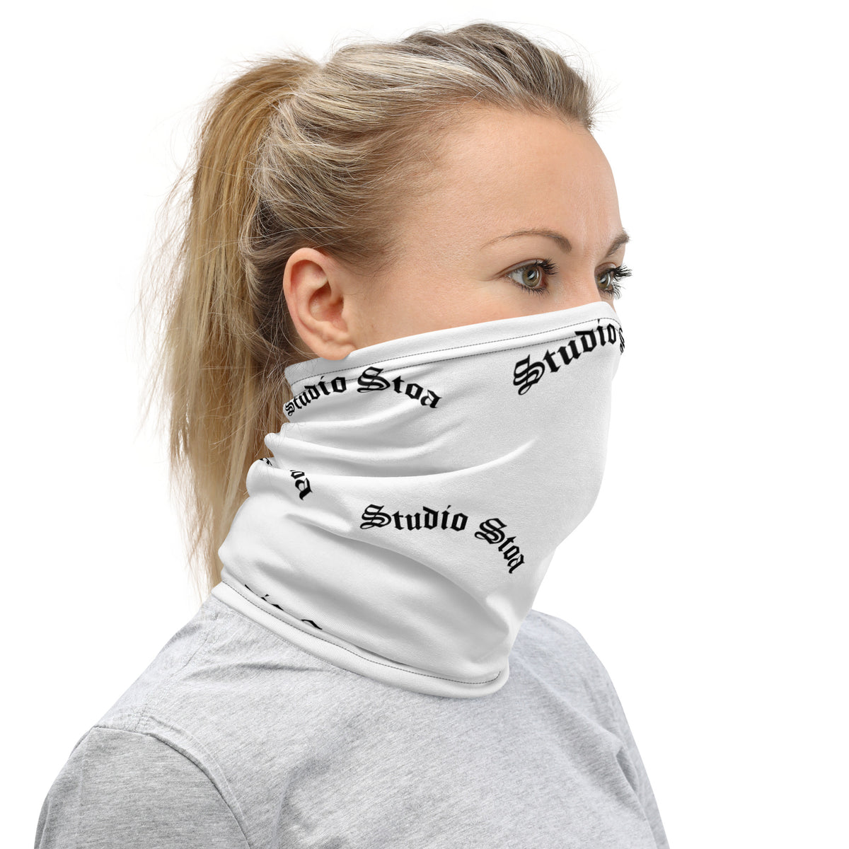 A woman wearing a white neck gaiter with a black 'Studio Stoa' logo print, shown in profile against a solid white background.