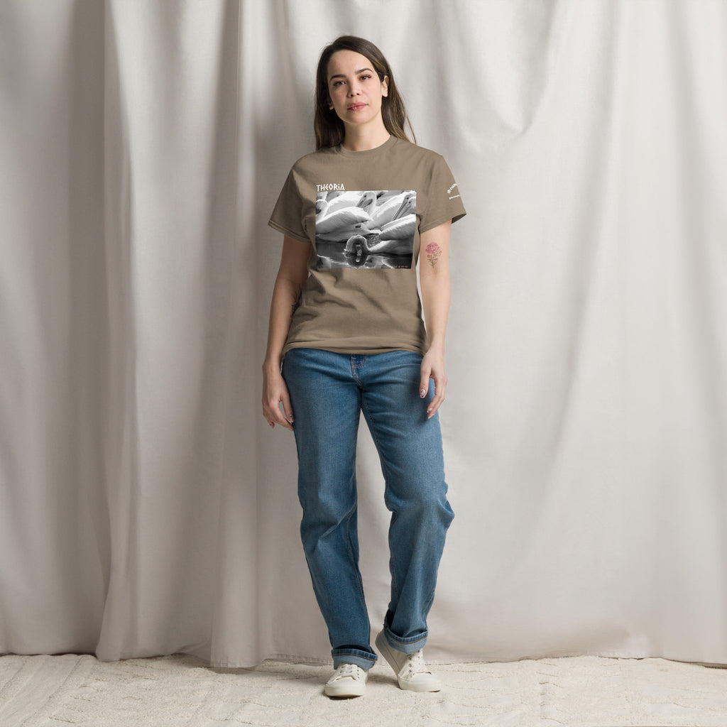 A woman modeling a light brown graphic t-shirt with a black and white photo of pelicans feeding on the water